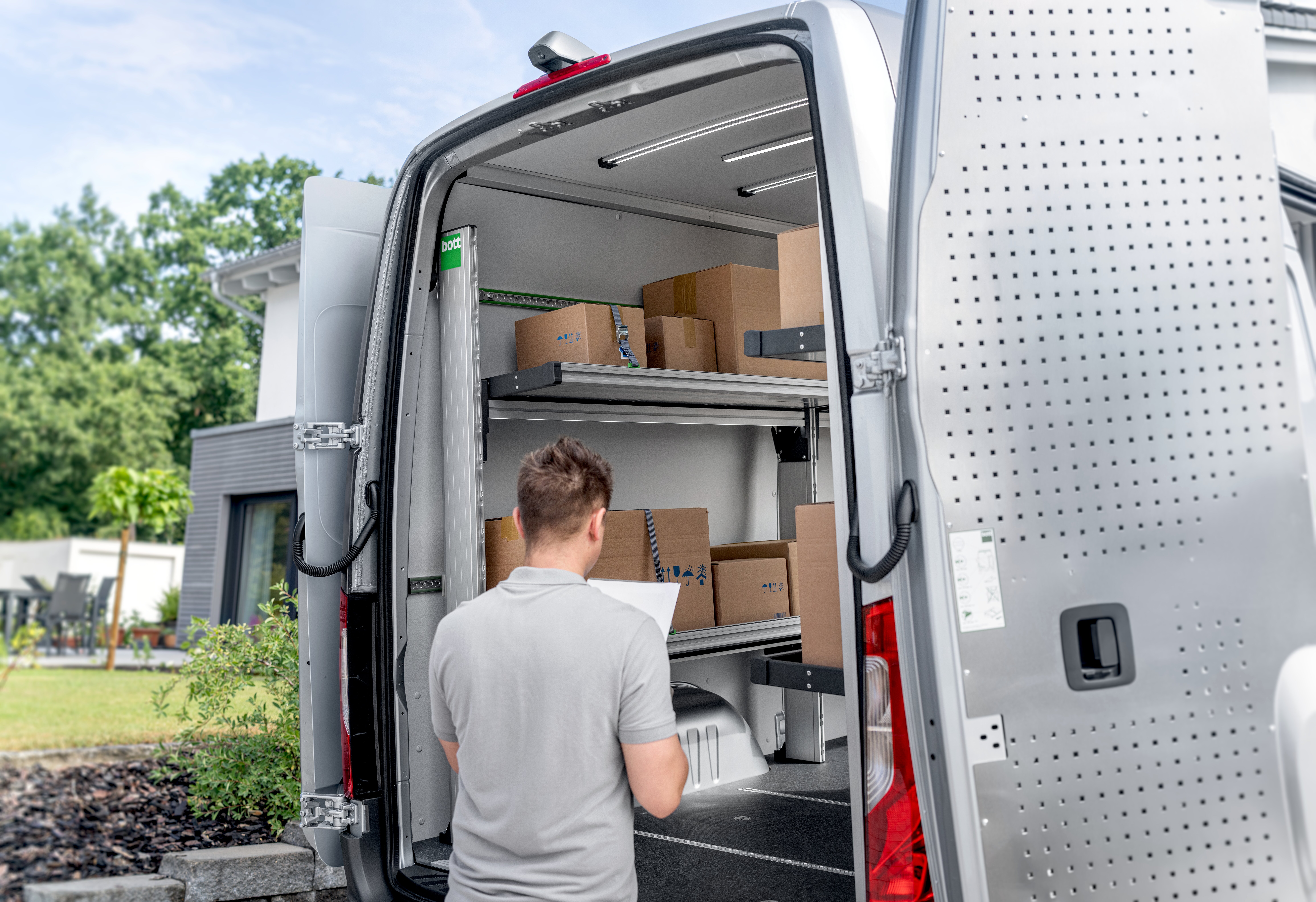 KEP-Zusteller entnimmt ein Paket aus dem mit bott vario3 Klappregalen ausgestatteten Transporter
